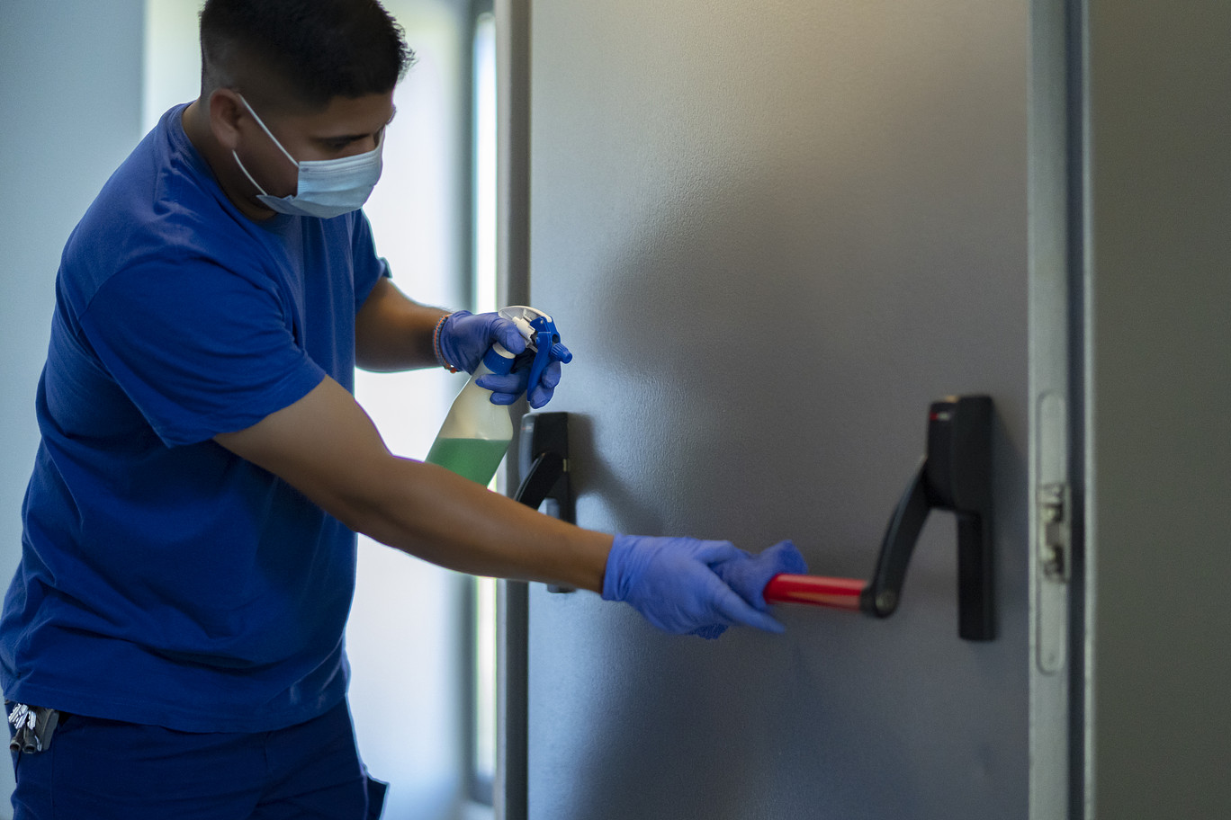 Hospital worker cleaning door handle